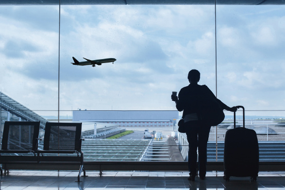 traveler in airport looking at the plane taking off